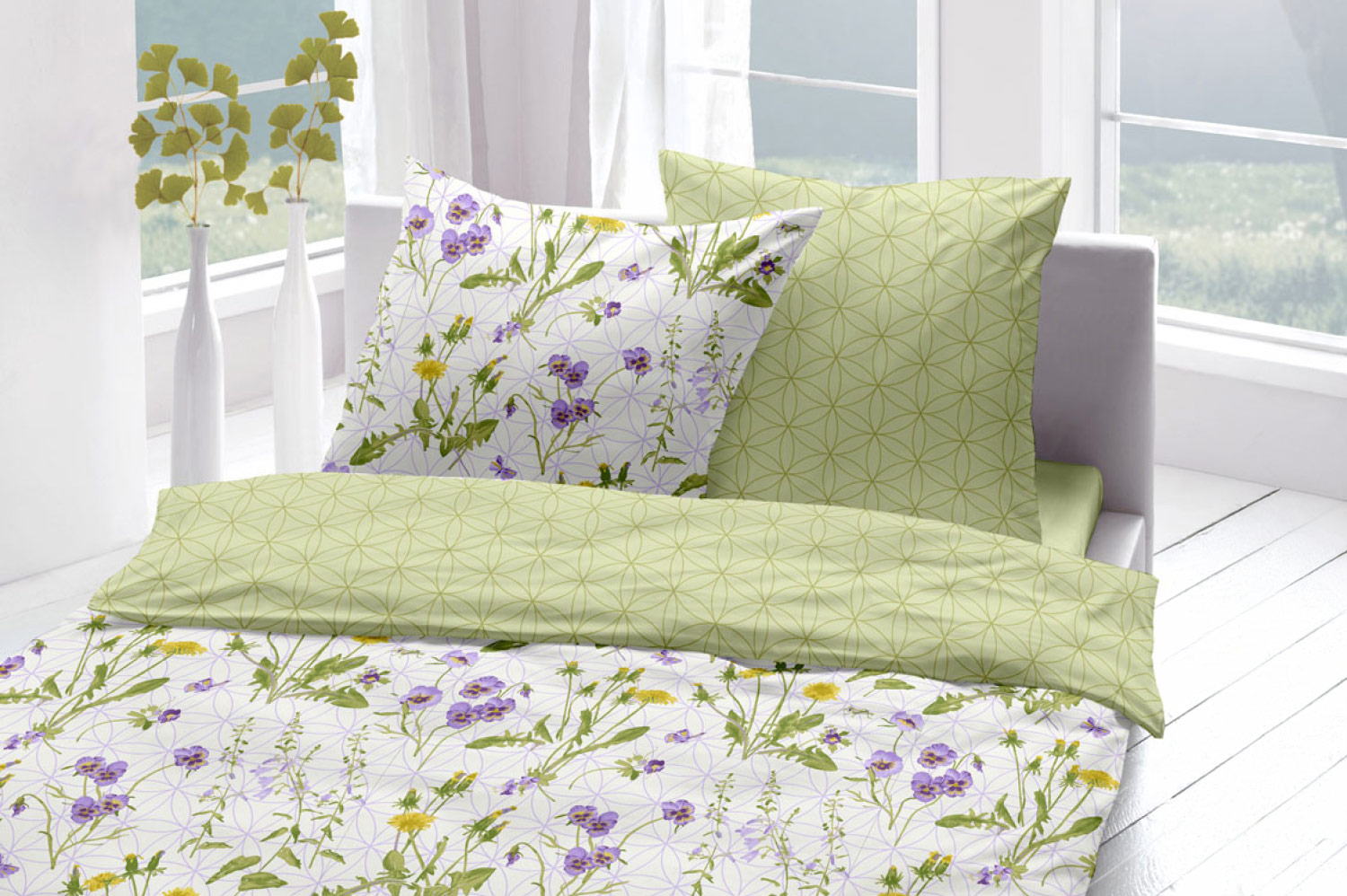 Frühlingshafte Wende-Bettwäsche mit einer zartgrünen Seite, die mit dem Muster der Blume des Lebens bedeckt ist. Die weiße Seite ist mit floralen Motiven aus Veilchen und Löwenzahn geschmückt.