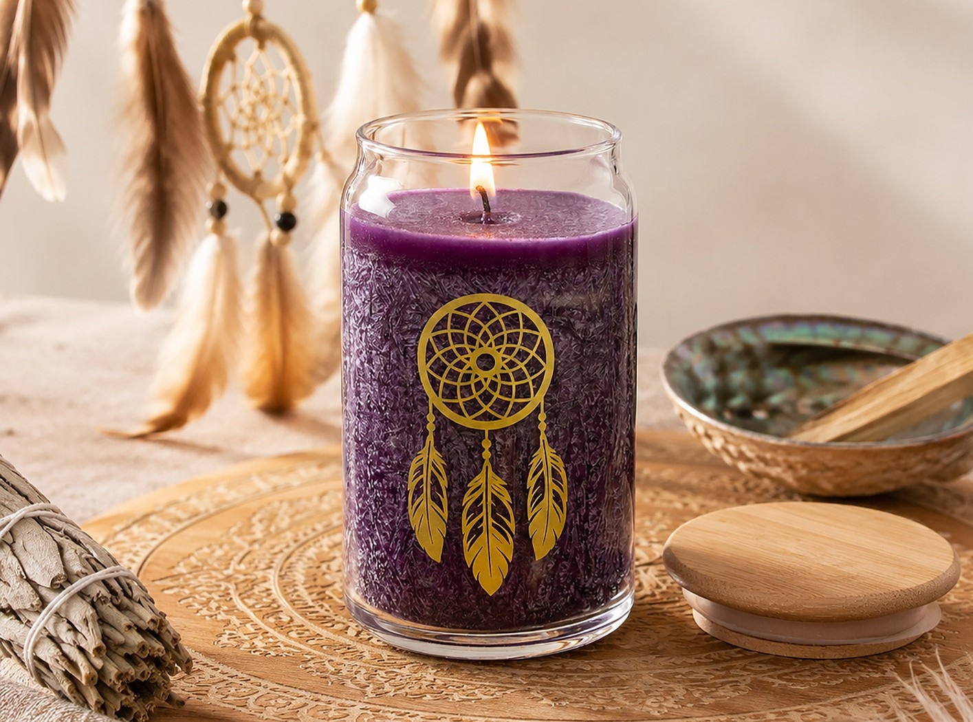 Violette Kerze im Glas mit goldenem Traumfänger-Motiv, umgeben von Federn, Räucherwerk und dekorativen Accessoires.