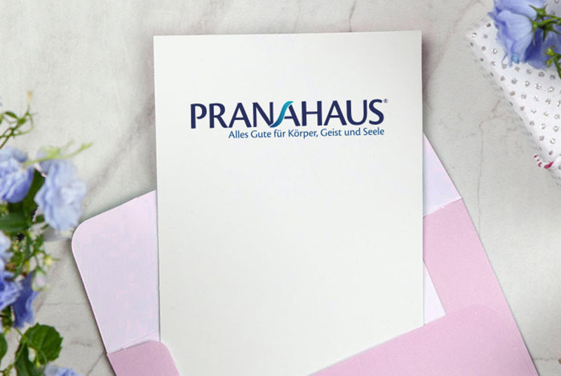 Karte mit PranaHaus-Logo in einem rosa Umschlag.