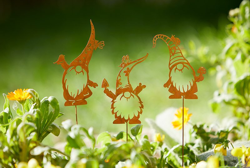 Drei Pflanzenstecker aus Edelrost, die kleine Wichtel mit Rauschebart und Zipfelmütze darstellen.