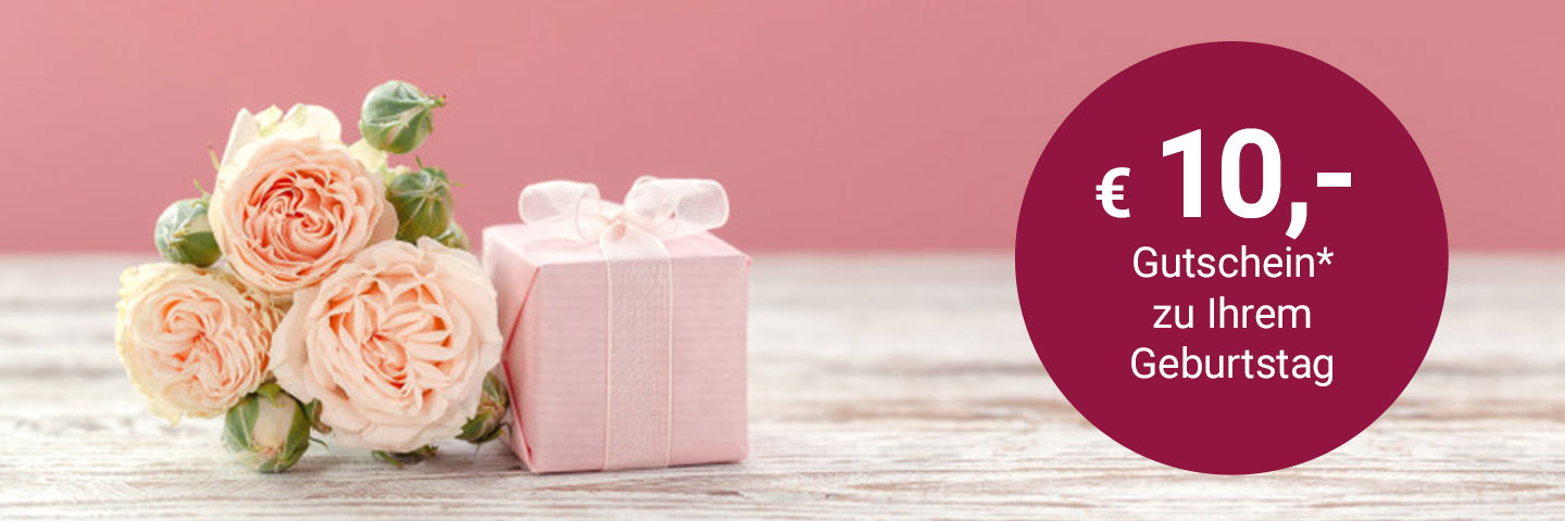 3 hellrosa Rosen liegen auf einem weißen Holztisch, daneben ein kleines, in rosa Papier eingepacktes Geschenk mit weißer Schleife. Rechts im Bild ein dunkelroter Kreis mit weißem Text: "10€ Gutschein zu Ihrem Geburtstag"