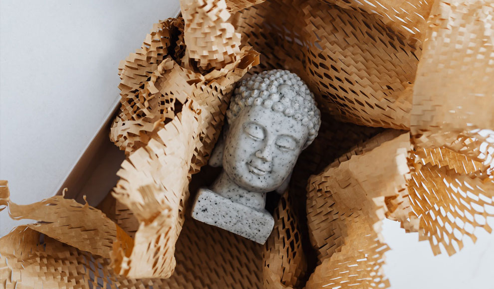 Eine kleine steinerne Budda-Statue liegt in einem geöffneten Päckchen.