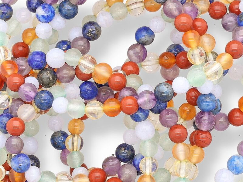 Detailansicht mehrerer Chakra-Armbänder aus bunten Edelsteinperlen in unterschiedlichen Farben. Die Perlen liegen locker verschlungen und stehen symbolisch für Balance, Energiefluss und die Vielfalt der sieben Chakren.