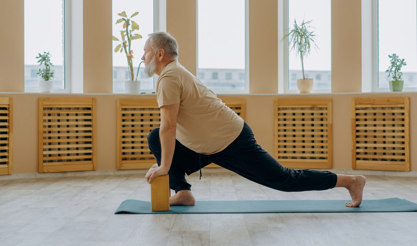 Ein älterer Mann mit Bart übt Yoga in der Wohnung