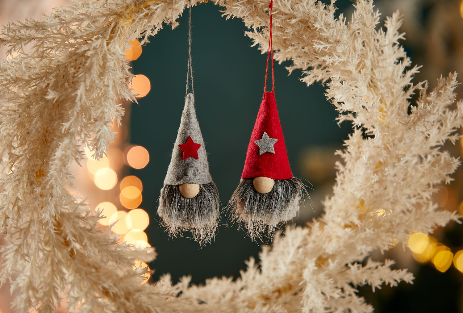 Zwei Wichtelfiguren, die an der Zipfelmütze aufgehängt sind. 