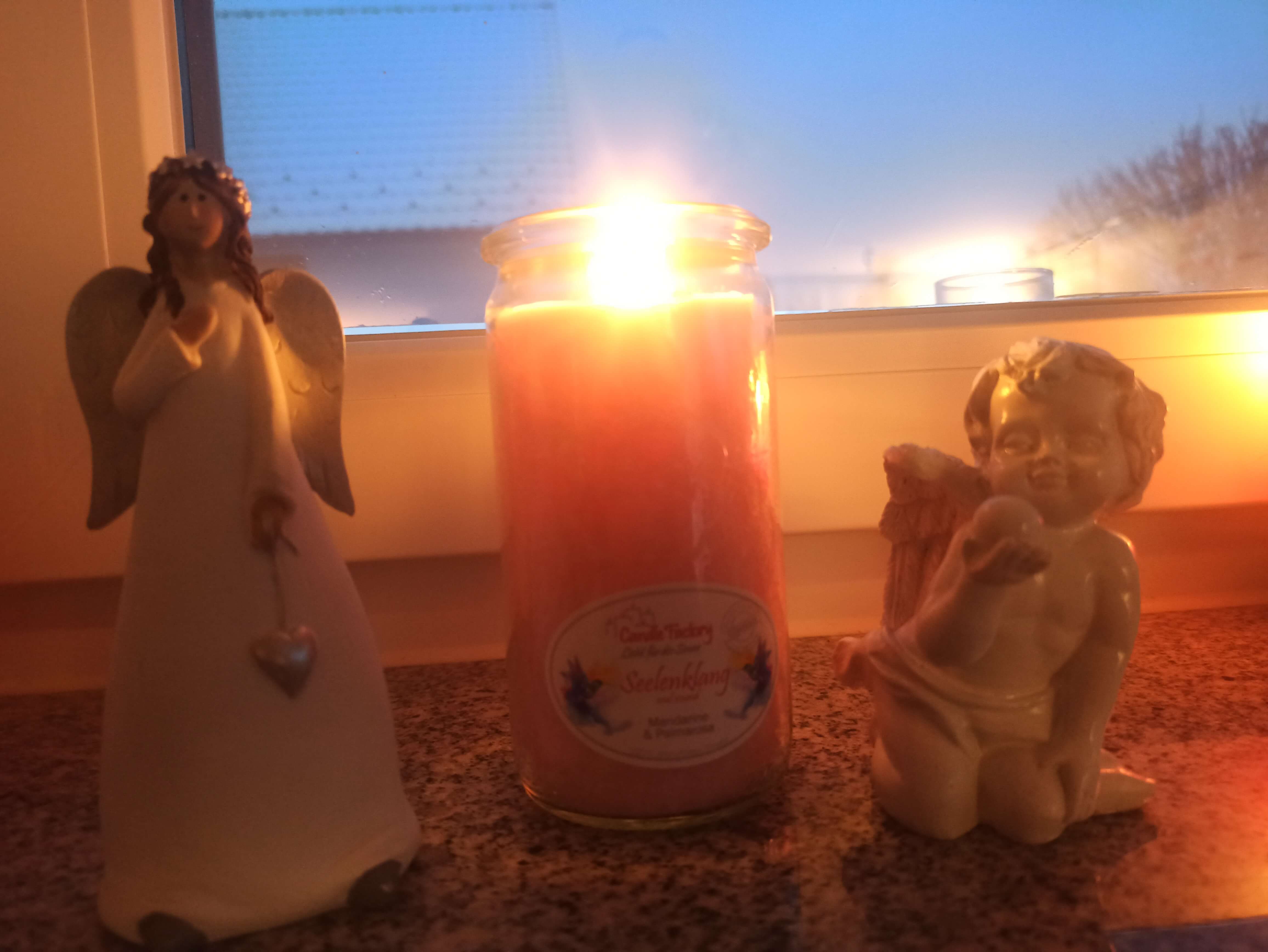 Brennende Kerze zwischen zwei Engelsfiguren